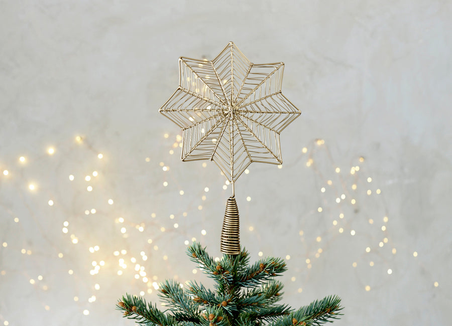 A delicate brass star hanging on a Christmas tree